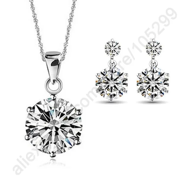 Conjunto de joyería de pedida de circonitas cúbicas de plata de ley que incluye un collar tipo gargantilla con colgante de diamante de talla redonda engastado, con cadena de acabado plateado a juego, y pendientes colgantes a juego con piedras facetadas brillantes, engastadas en metal pulido.