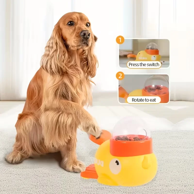 Interactive Dog Feeding Toy | Automatic Cartoon Duck Design A long-haired Cocker Spaniel sitting on a white rug, pressing a large orange lever on a yellow duck-shaped interactive dog feeding toy with its paw. Inset diagrams show Step 1: "Press the switch" and Step 2: "Rotate to eat," demonstrating how the toy dispenses food from a clear top dome.