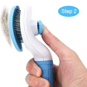 Self-Cleaning Pet Brush | Dogs & Cats, Grooming Tool A close-up shot of a person using a white and blue pet deshedding brush on the thick tan fur of a large dog outdoors.