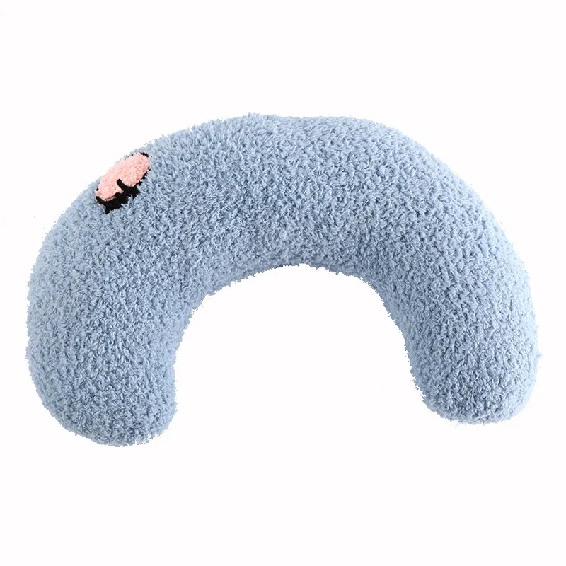 A blue, crescent-shaped neck pillow with a textured surface and a small pink cartoon face on one end, made from soft and cozy material for calming and anxious relief, The Stuff Box Cozy Pet Pillow for Cats and Small Dogs.