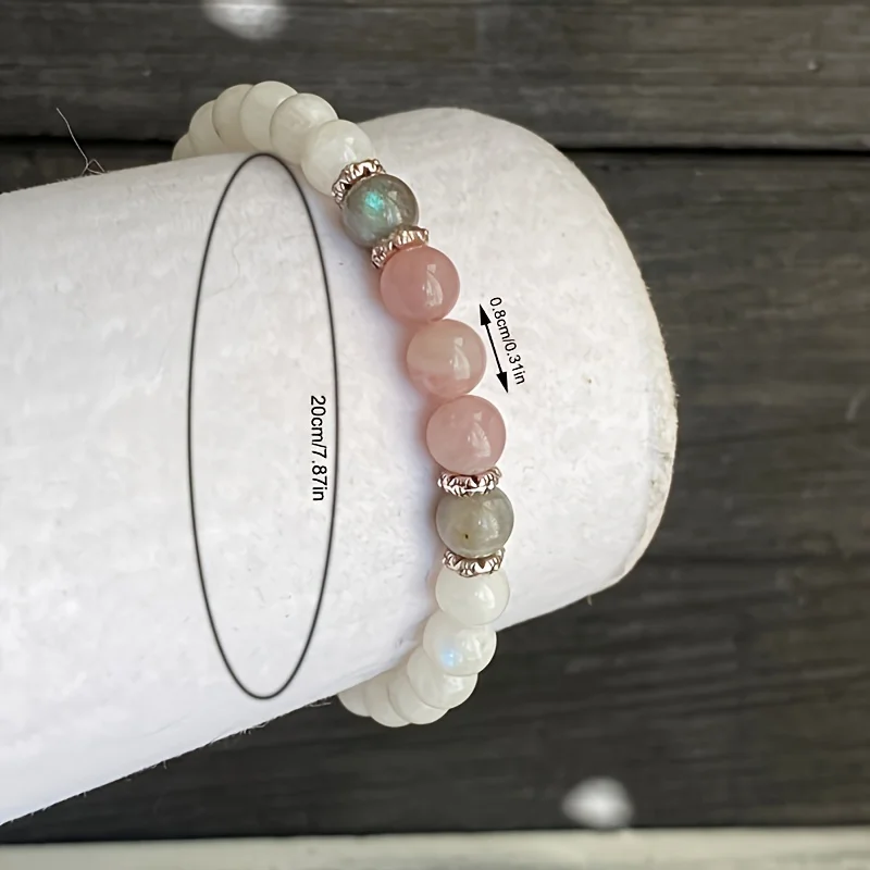 Healing gemstone bracelet resting on a fabric pouch with moonstone, labradorite, and rose quartz