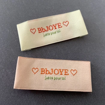 

Factory Price Customized pink background labels In 50D High Density Woven Labels Clothing Labels