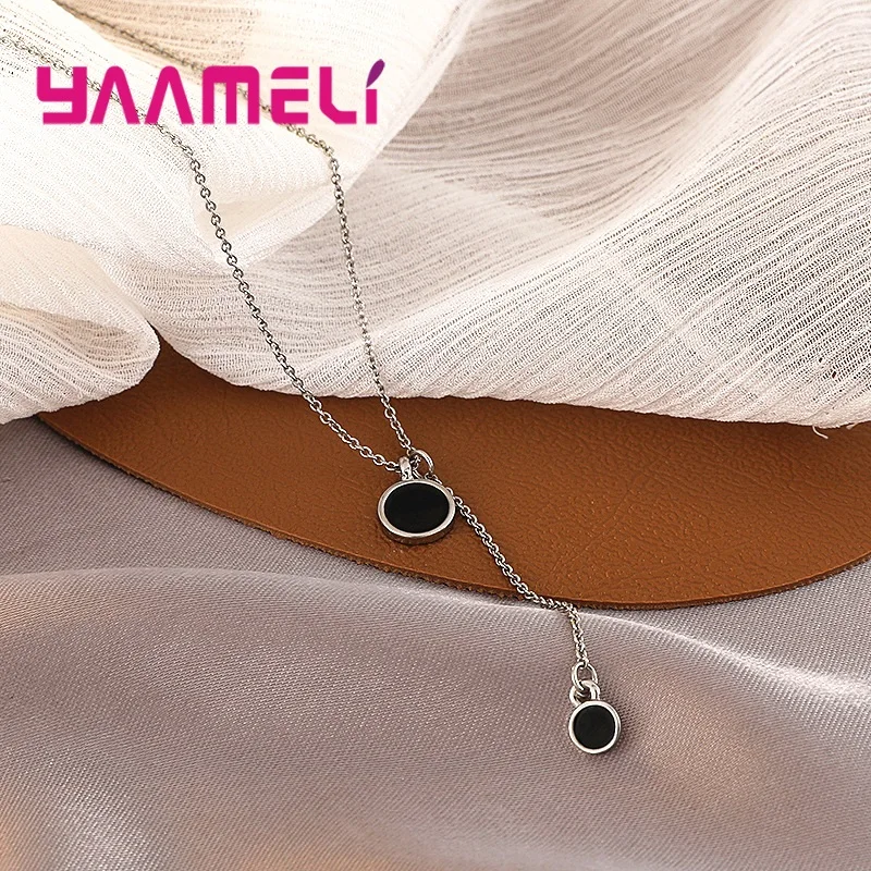 Collar de plata de ley con un diseño elegante y minimalista que incorpora dos dijes circulares negros.
