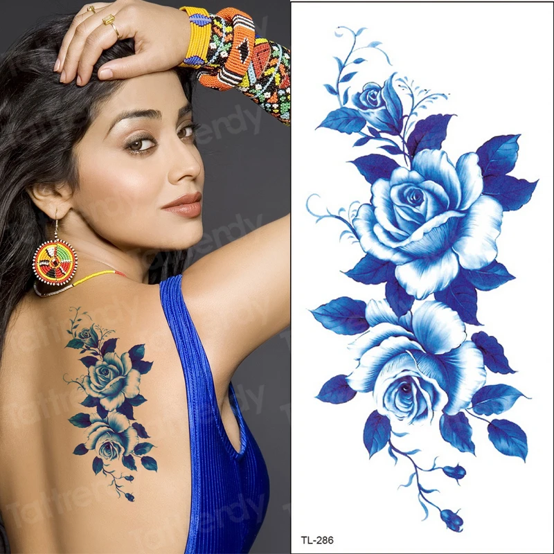 Mulher sexy com tatuagem segurando uma flor de strelitzia em um fundo azul  com espaço de cópia