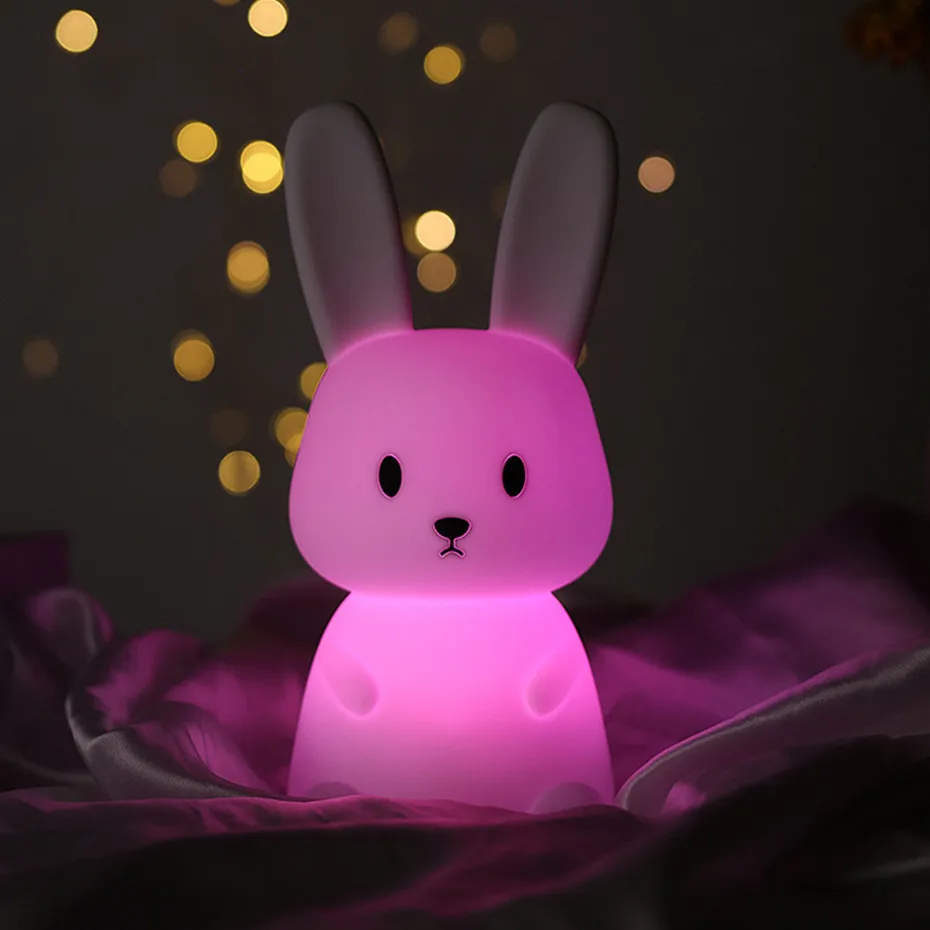 An adorable pink bunny night light, creatively designed and placed on a bed.