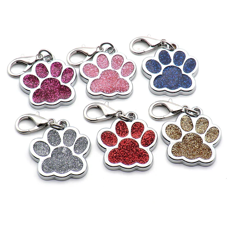 Six paw-shaped keychains with glittery finishes in various colors (pink, purple, blue, silver, red, and gold) are displayed against a white background. These High Quality Engravable Pendants for Dogs and Cats 100Pcs from The Stuff Box double as personalized paw ID tags that combine style and function for pet lovers.