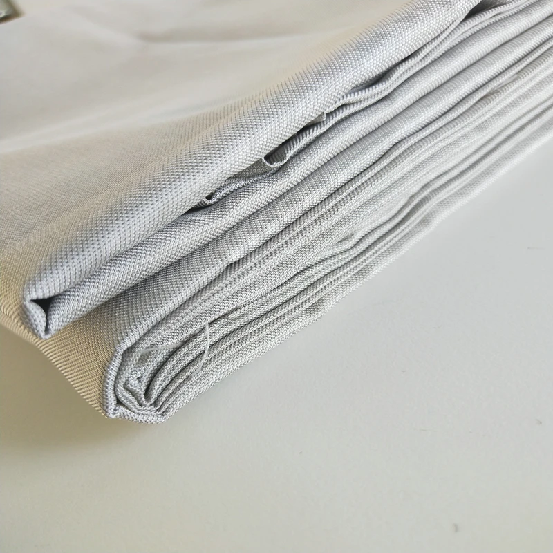 Échantillon du tissu antistatique anti-radiation en fibre d'argent, avec une règle pour montrer l'épaisseur et la flexibilité du matériau.