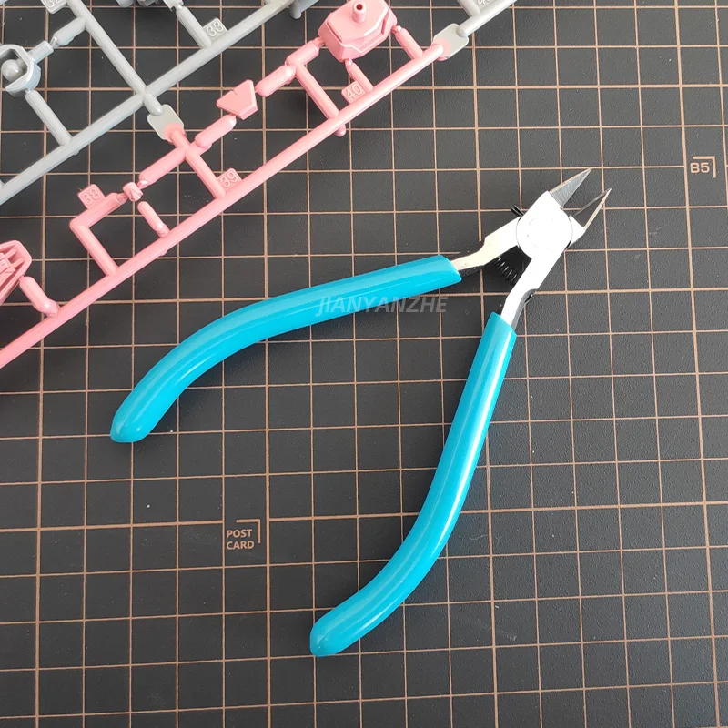 Pince à buse à lame fine utilisée sur une maquette en plastique, outil de précision pour modélisme.