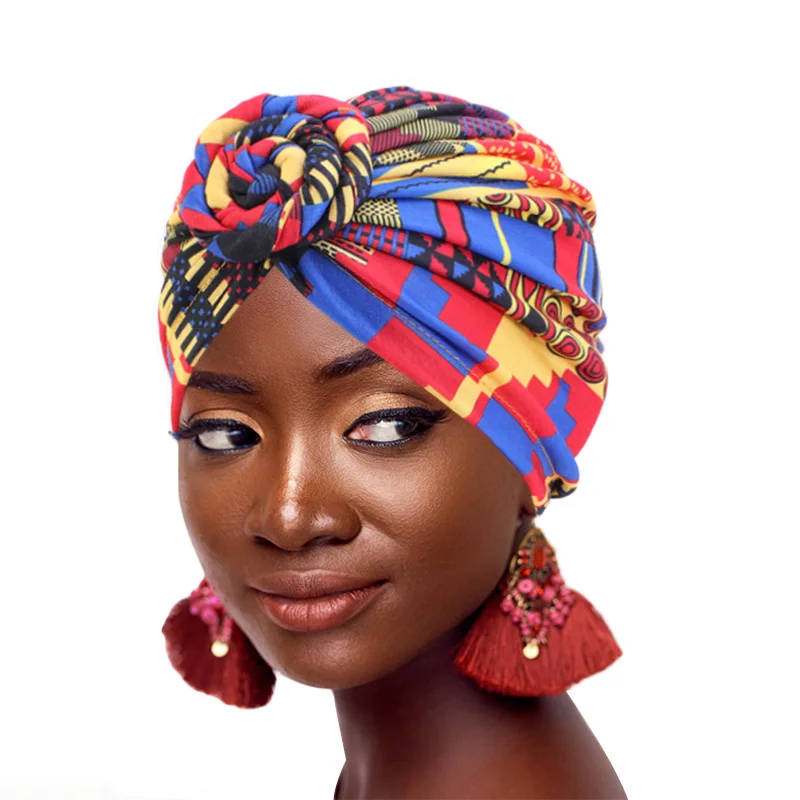 Une jeune femme de couleur porte un turban multicolore sur la tête , elle est présentée sur fond blanc