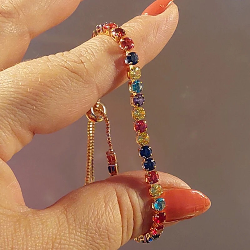 A person holding up a Rainbow Zircon Chain Tennis Bracelet for Women, showcasing women's fashion trends.