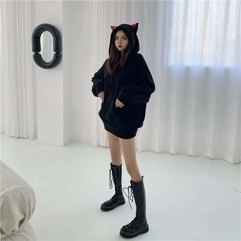 a model wearing a black color cat themed hoodie with red color ears