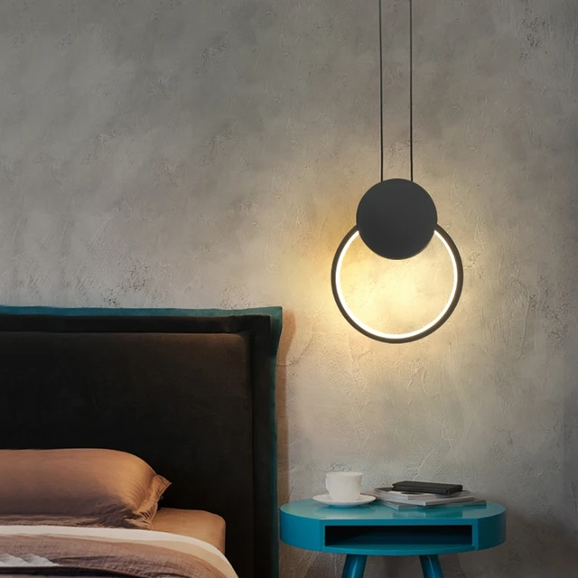 Suspension LED design minimaliste anneau noir au dessus d'une table de chevet pres d'un lit