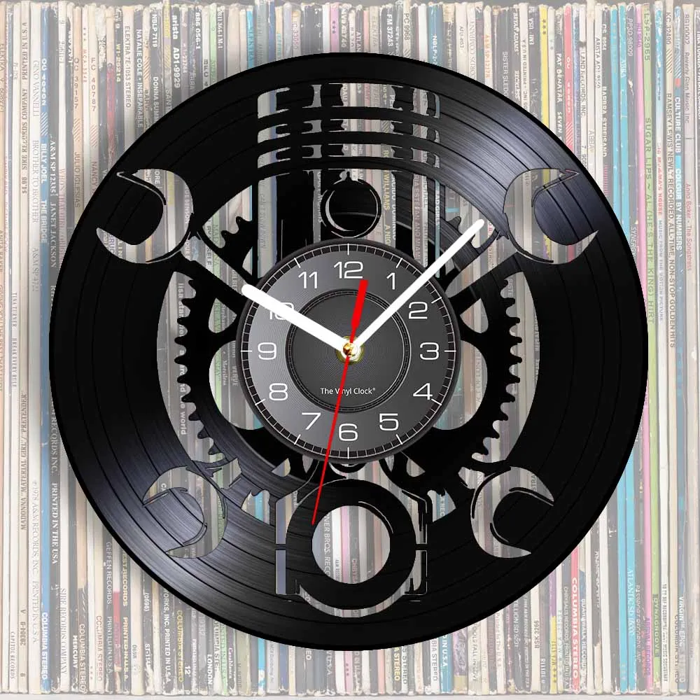 Introducing the Black Record Wall Clock: a rustic industrial timepiece crafted from black vinyl, adorned with intricate gears and wrench cut-outs, set against a backdrop of stacked vinyl albums.