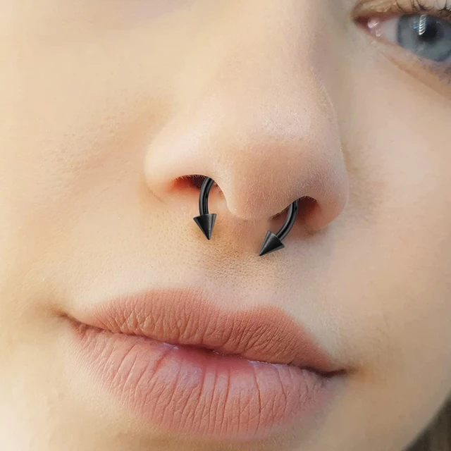 Homem com piercing na sobrancelha. três pequenos piercings pretos.