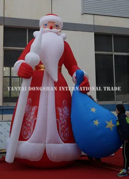 

Giant inflatable Santa Claus standing with stick and gift package in hands for Christmas event decoration