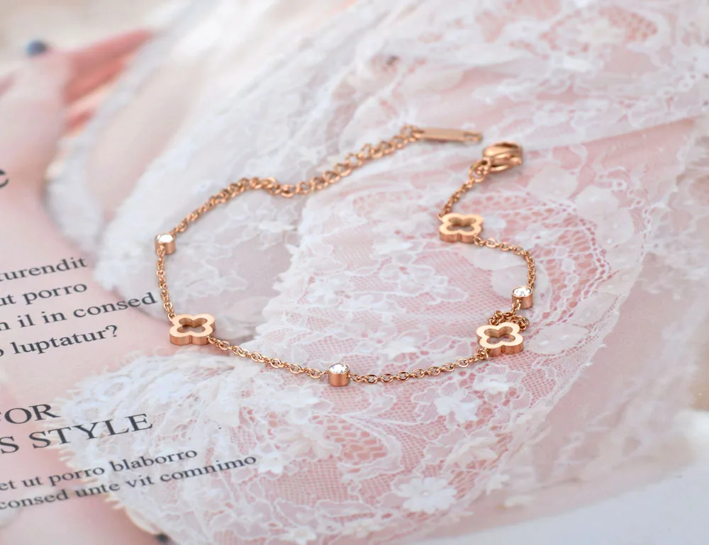 A woman donning a fashionable white dress and accessorized with a Chain Charm Bracelet For Women Heart / Flower Designs.