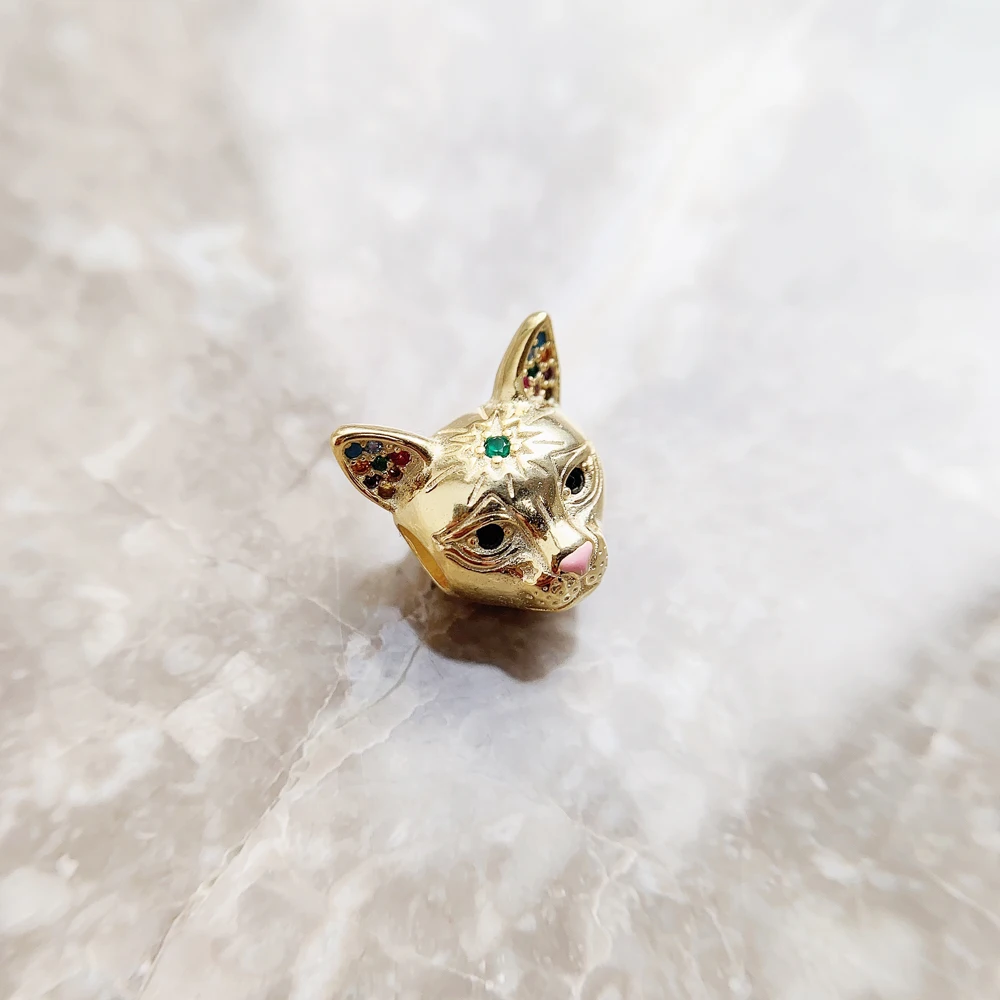 A luxury gold plated cat head charm bead with an emerald green forehead stone and pink enamel nose showing dimensions on a digital caliper