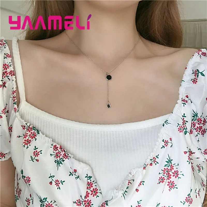 Un delicado collar con dije doble círculo negro y plata de ley con una cadena con acabado dorado y un dije colgante con forma de gota que presenta el logotipo de la marca yameli.