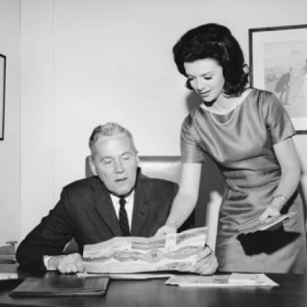 Businessman looking at a map with his secretary standing beside him Poster Print (24 x 36) | Дом и сад