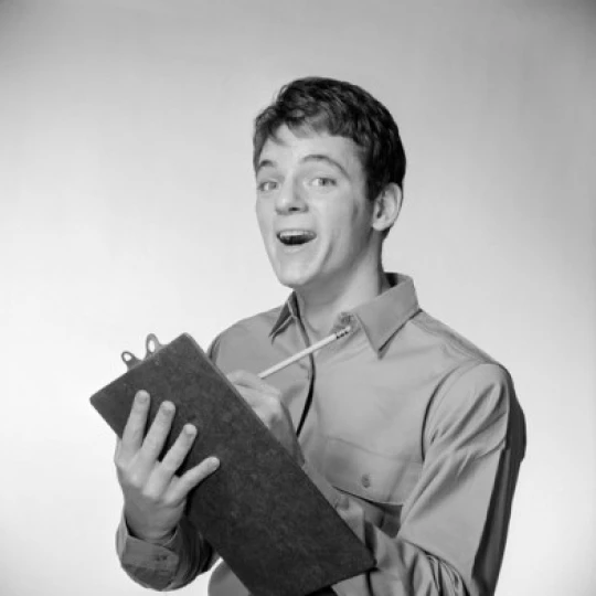 Young man holding writing pad making a face Poster Print (24 x 36) | Дом и сад