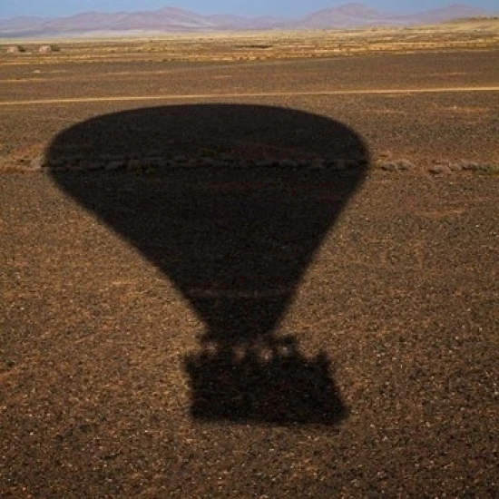 Hot air balloon casting a shadow over Namib Desert  Sesriem  Namibia Print by David Wall (18 x 24)