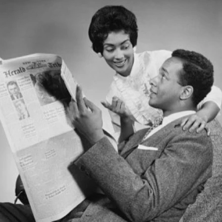 Side profile of a young man holding a newspaper with a young woman standing beside him Poster Print (24 x 36)