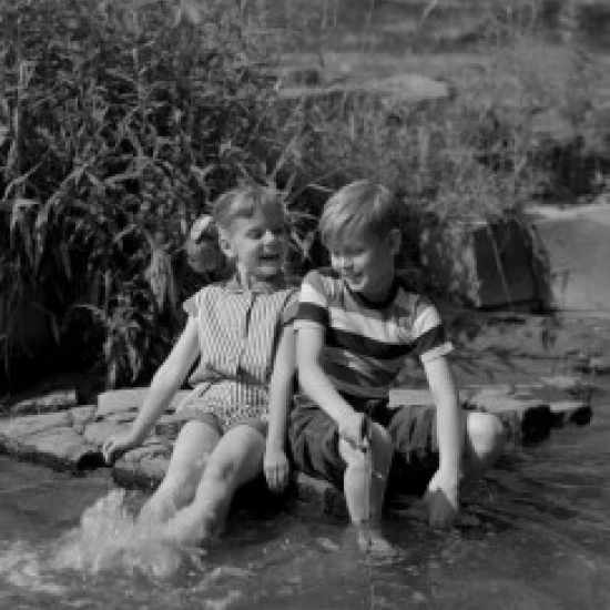 Girl and boy sitting with legs in lake Poster Print (24 x 36)