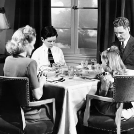 Mid adult couple praying with their children before having breakfast Poster Print (18 x 24)