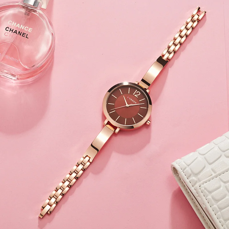 A Ultra Thin Romantic Clock Women's Watch on a pink background next to a purse.