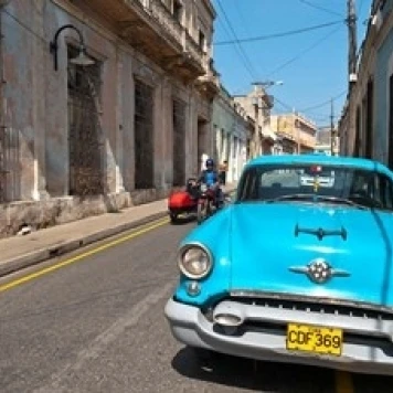 Cuba  Camaquey  Oldsmobile car and buildings Poster Print by Bill Bachmann (29 x 19)