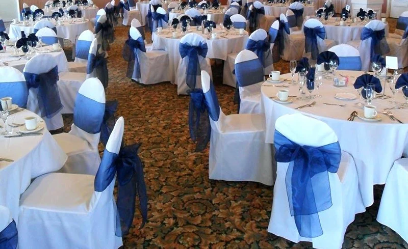 organza-chair-covers-white-and-ivory-chair-covers-available-for-rent-with-navy-blue-organza-bows-in-beach-organza-chair-sash-bows