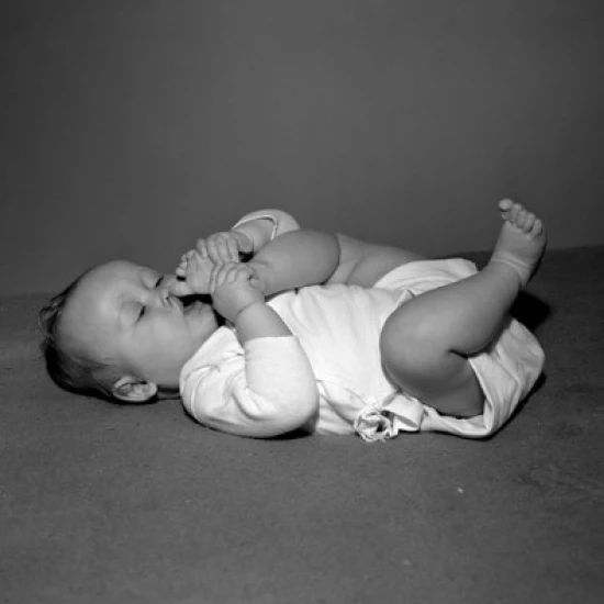 Baby girl lying on back  sucking toes Poster Print (18 x 24)