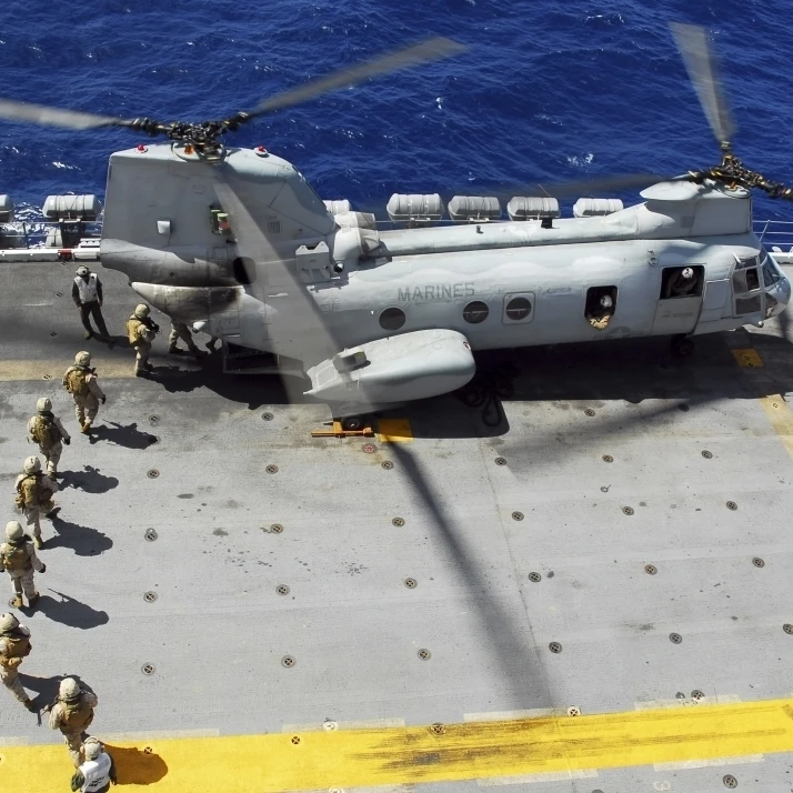 Marines board a CH-46E Sea Knight helicopter on the flight deck of USS Peleliu Poster Print (32 x 23)