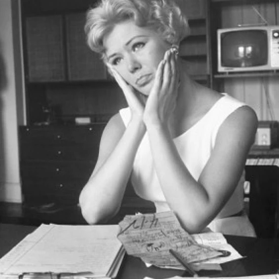 Close-up of a young woman sitting at a table and looking worried Poster Print (18 x 24)