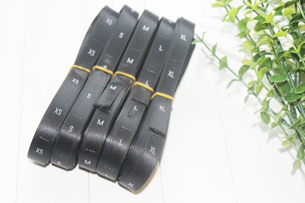 

Stock roll 1.2*3.3cm satin polyester woven size labels black fabric white letters XS S M L XL XXL 500pcs lot