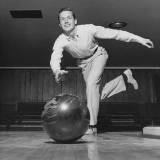 Low angle view of young adult man bowling Poster Print (18 x 24)