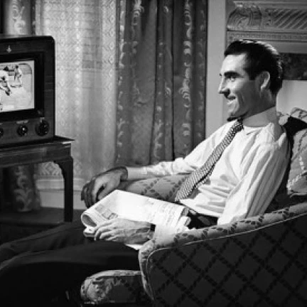 Mid adult man watching television Poster Print (24 x 36)
