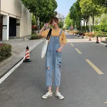 Комбинезон с дырками; джинсовые комбинезоны; сезон осень-зима; синие фактурные карманы на лямках; свободные брюки до щиколотки; джинсовые джинсы