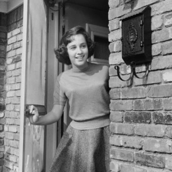 Teenage girl standing at a door and smiling Poster Print (18 x 24)