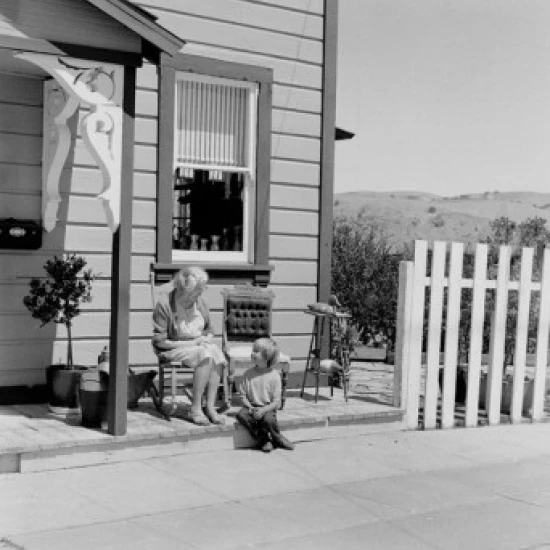 Grandmother and grandson sitting outside house Poster Print (24 x 36)