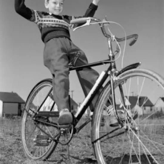 Boy riding bicycle with arms raised Poster Print (24 x 36)