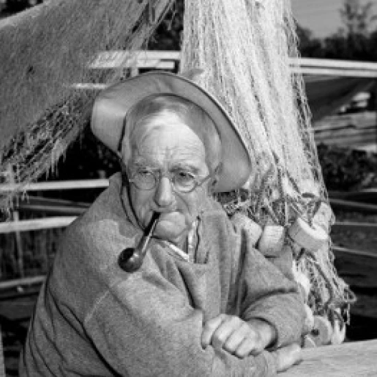Portrait of fisherman with pipe  fishing net in the background Poster Print (18 x 24)