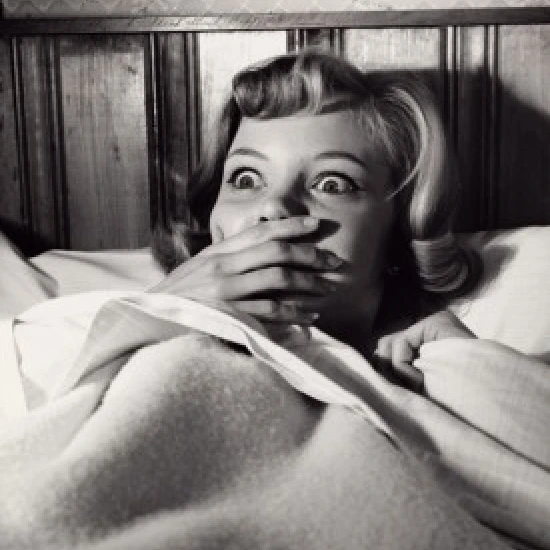 Close-up of a young woman lying in bed looking frightened Poster Print (24 x 36)