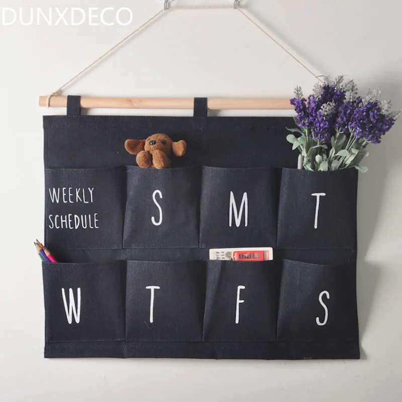 

DUNXDECO 1PC Modern Jean Weekly Linen Cotton Storage Pocket Hanging Home Office Storage Organiser Hanging Decoration Gift