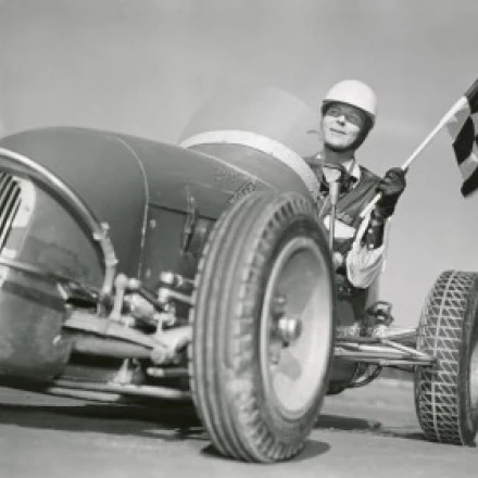 Mid adult man driving a car and holding a checkered flag Poster Print (18 x 24)
