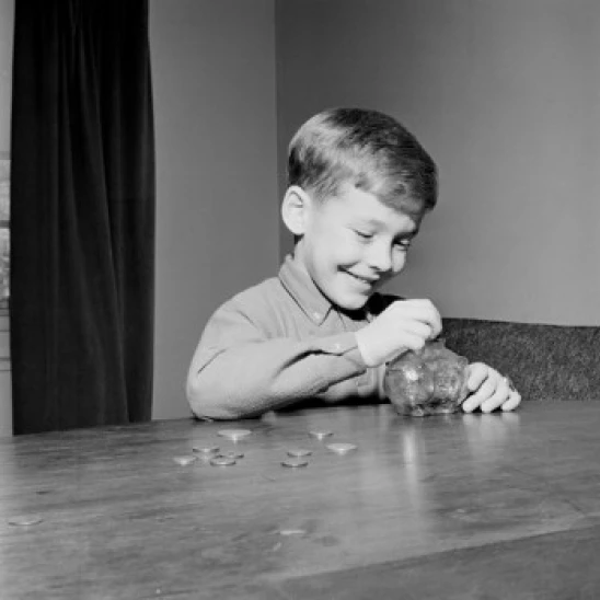 Young boy putting coins in piggybank Poster Print (24 x 36)