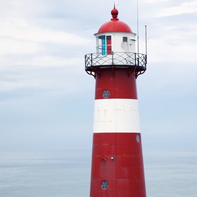 Red and white lighthouse along the coast with a sailboat in the distance near westkapelle;Zealand  netherlands (38 x 24)
