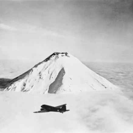 USA  Aleutian Islands  Naval Air Transport flying towards Attu above snow capped Caroloi volcano Poster Print (24 x 36)