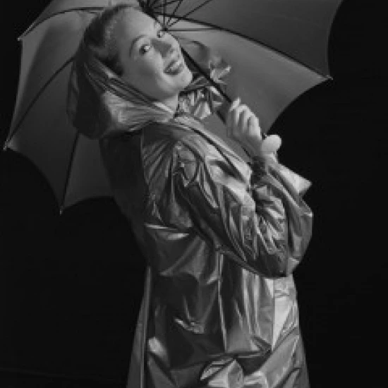 Young woman holding umbrella and wearing raincoat Poster Print (24 x 36)