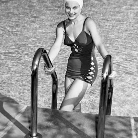 Portrait of young woman climbing ladder of swimming pool Poster Print (24 x 36)